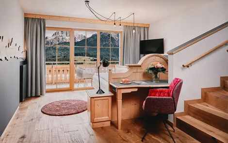 Stoaberg Gemütliches Hotelzimmer mit Schreibtisch, Holzboden und Blick auf die Alpen